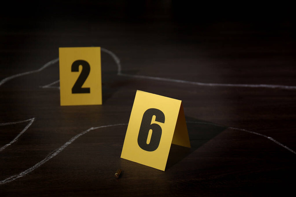 Crime scene with chalk outline of human body, bullet shell and evidence markers on wooden floor. Detective investigation - Zdjęcie, obraz