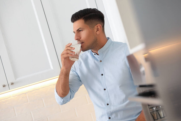 Man drinking pure water from glass in kitchen - Fotoğraf, Görsel