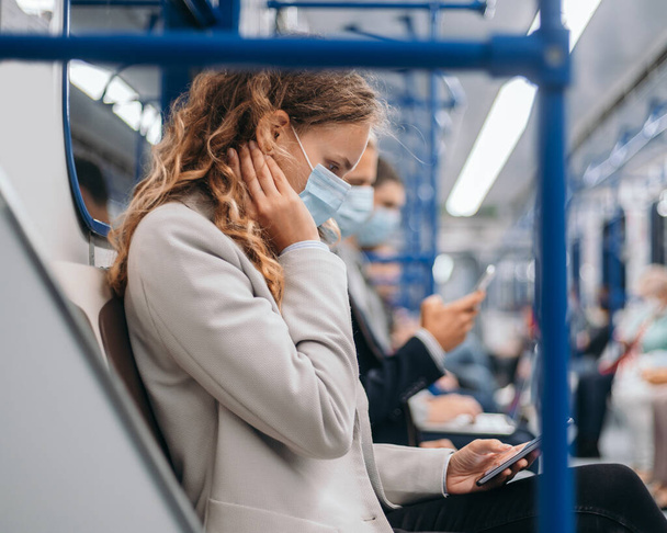 passengers in protective masks using their gadgets in the subway car . - Foto, afbeelding