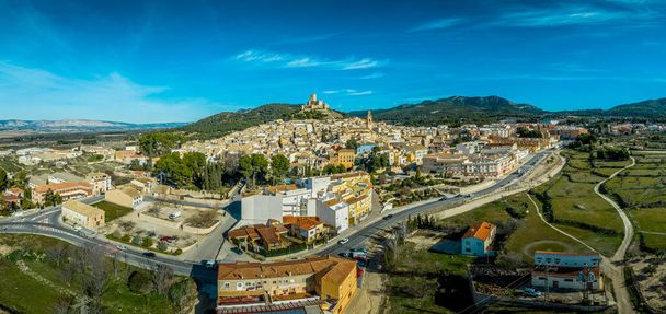 Αεροφωτογραφία του κάστρου Biar στην επαρχία Βαλένθια της Ισπανίας με donjon πανύψηλα πάνω από την πόλη και ομόκεντρα τείχη ενισχυμένα με ημικυκλικούς πύργους σε μια ηλιόλουστη μέρα με γαλάζιο ουρανό - Φωτογραφία, εικόνα