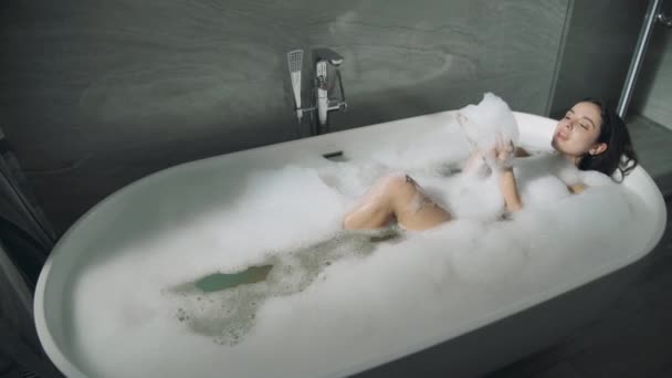 Aranyos lány, aki a kádban fekszik. Édes hölgy élvezi buborék fürdőkád. - Felvétel, videó