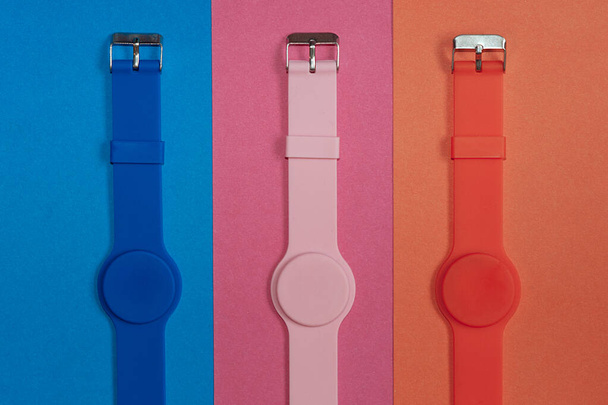 Três relógios de silicone limpos para fitness e esportes. Acessórios de mão de silicone azul, rosa e laranja. Tricolor. - Foto, Imagem