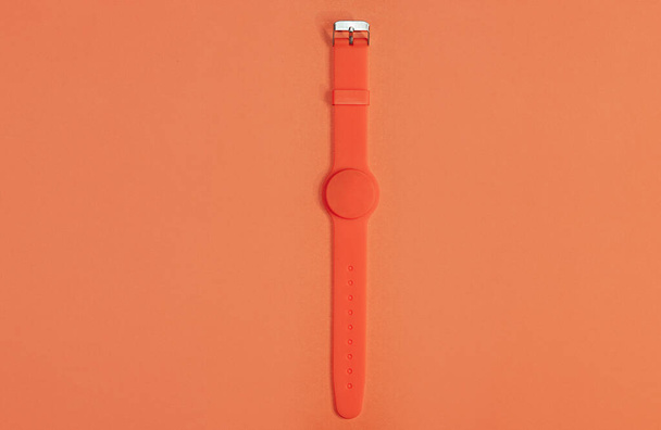 Relógio de silicone laranja com sensor magnético em um fundo laranja claro. Imagem monocromática. Estilo de vida saudável, monitorar sua saúde - Foto, Imagem