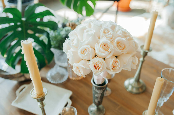 ヴィンテージスタイルで提供される木製のテーブルの上に新鮮なきれいな同一のバラの白い花束。ヴィンテージスタイルの結婚式の装飾. - 写真・画像