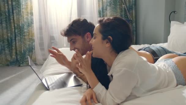 Smiling couple having video call laptop in bed. Couple looking computer screen. - Záběry, video