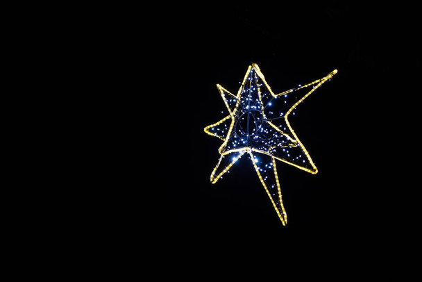 Dekorativer Weihnachtsstern aus LED-Lampen auf schwarzem Hintergrund. Weihnachts- und Neujahrskonzept. - Foto, Bild