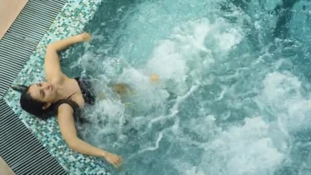 Kalme dame met hydromassage in de spa. Ontspannen vrouw ontspannen in whirlpool indoor - Video
