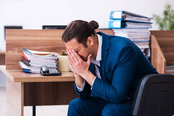 Mladý muž zaměstnanec nešťastný s nadměrnou prací v kanceláři - Fotografie, Obrázek