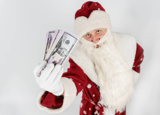 New Year and Christmas concept. Santa Claus holds money in his hands. Isolated on light background - Fotoğraf, Görsel