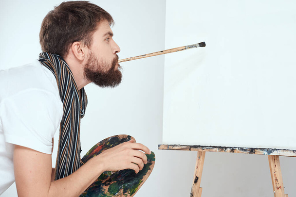 Αρσενικό καλλιτέχνη ζωγραφίζει σε easel παλέτα τέχνης δημιουργικότητας φως φόντο - Φωτογραφία, εικόνα