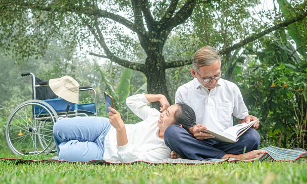 Glücklicher behinderter Großvater entspannt mit Enkelin im Freien im Park. Familienfreundlicher Lebensstil. - Foto, Bild
