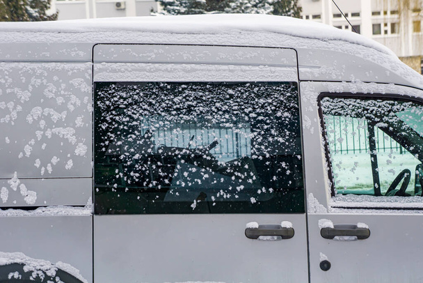 Voiture congelée, mini-fourgonnette blanche couverte de neige le jour d'hiver. Scène urbaine de la vie urbaine en hiver dans la tempête de neige. - Photo, image
