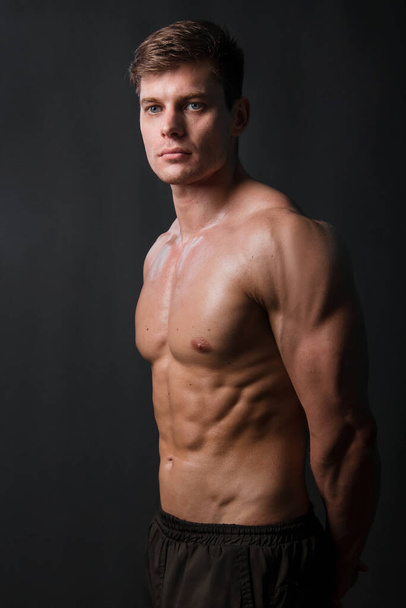 Muscular bodybuilder posing with a naked torso against a black background. Sexy man. - Fotografie, Obrázek