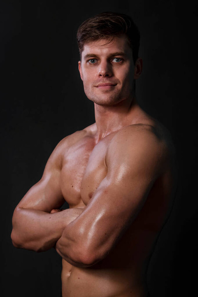 Muscular bodybuilder posing with a naked torso against a black background. Sexy man. - Foto, immagini