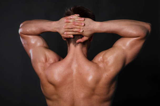 Muscular bodybuilder man posing on black background. View from the back. - Valokuva, kuva