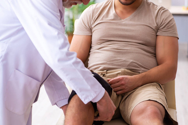 Experienced doctor traumatologist examining young male patient - Photo, Image