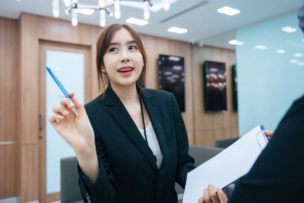 Krásná mladá asijská podnikatelka nosit černou bundu dávat rady partnerovi v kanceláři. - Fotografie, Obrázek