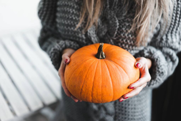 Woman with red nails holding a pumpkin - Foto, Imagen