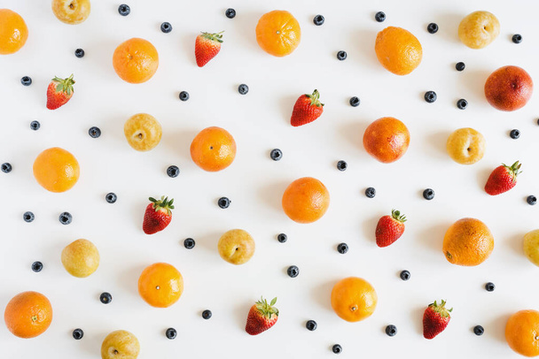 Fruits and berries on white background, overhead view. Fruit pattern. Yellow plum, strawberry, blueberry and orange - Photo, Image