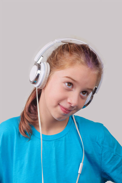 A brown eyed girl wearing headphones and listening to music - Φωτογραφία, εικόνα