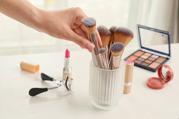 Žena bere make-up kartáč z toaletního stolku - Fotografie, Obrázek