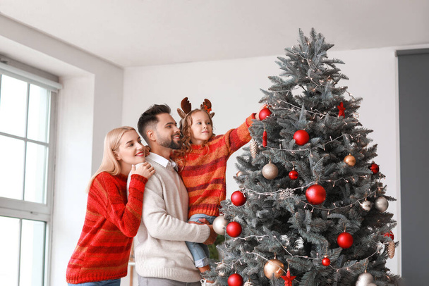 Νεαρή οικογένεια διακόσμηση χριστουγεννιάτικο δέντρο στο σπίτι - Φωτογραφία, εικόνα
