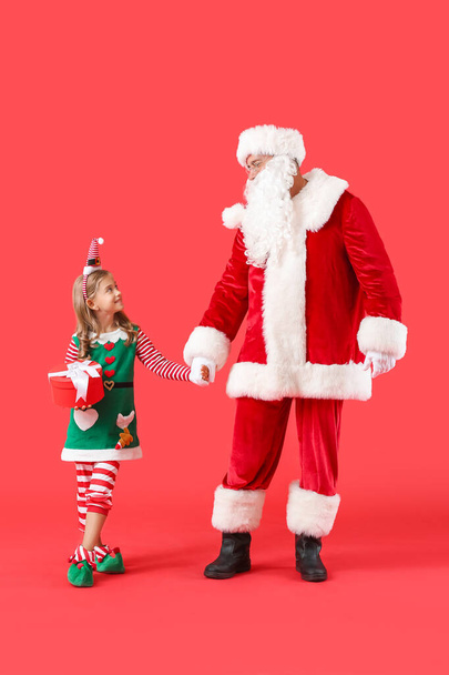 Cute little elf with Santa Claus and Christmas gift on color background - Φωτογραφία, εικόνα