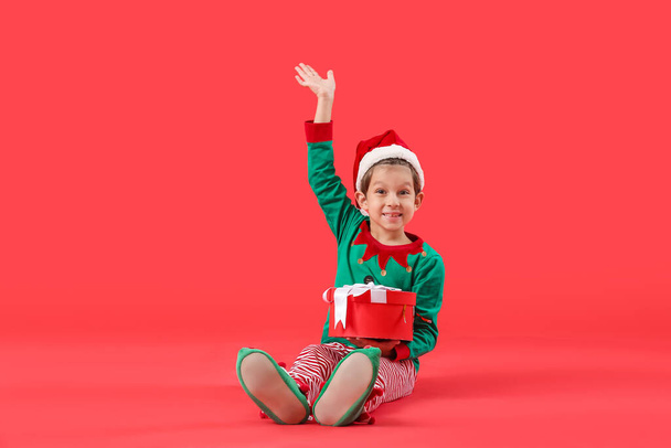 Lindo pequeño elfo con regalo de Navidad en el fondo de color - Foto, imagen