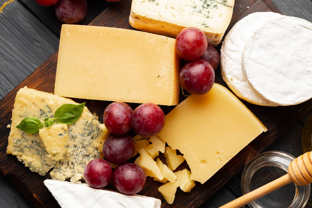 Cheese served with grapes and honey on grey surface - Photo, image