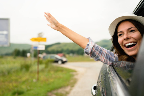 Woman in car road trip waving out the window smiling. Travel, fun, vacation concept. - Foto, Imagem