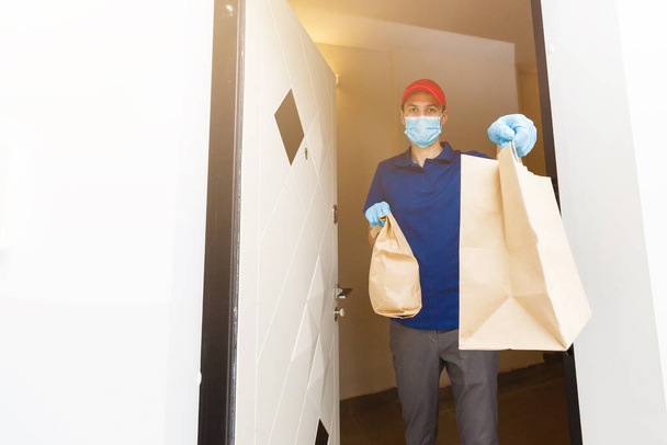 Livraison homme tenant des boîtes en carton dans des gants en caoutchouc et masque. Achats en ligne  - Photo, image