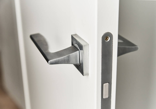 Tirador de puerta plateado en puerta blanca. Accesorios para muebles, elemento interior - Foto, imagen