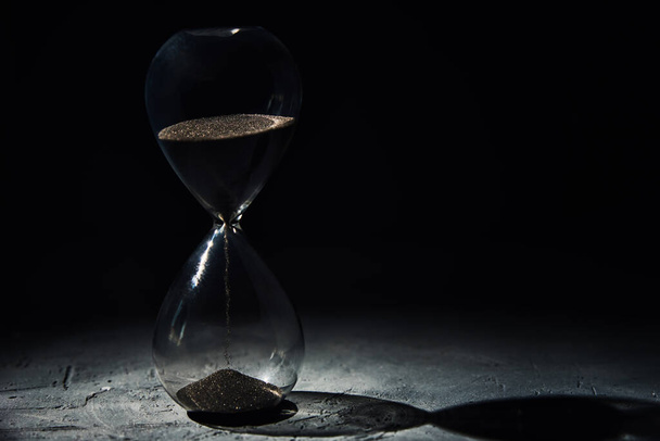 Hourglass on dark background, close up. Urgency and running out of time concept - Photo, Image