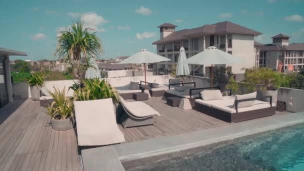 Camera Dolly shot van recreatiegebied op terras van chique hotel met chase-lounge, zwembad en groen - Video