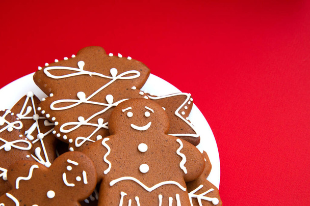 Tasty homemade Christmas gingerbread cookie of various shapes with sugar glaze on a bright red background with copy space. Close up - Photo, Image