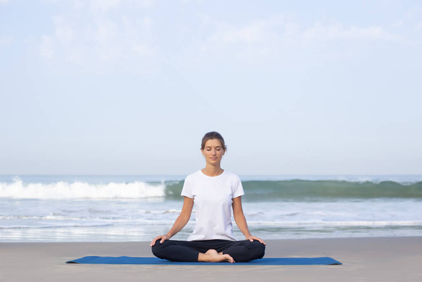 young girl on the beach doing yoga. in white clothes - Foto, Imagem