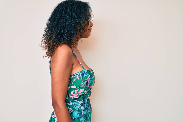 Giovane donna afroamericana indossa abiti casual cercando di lato, posa profilo relax con viso naturale con sorriso fiducioso.  - Foto, immagini