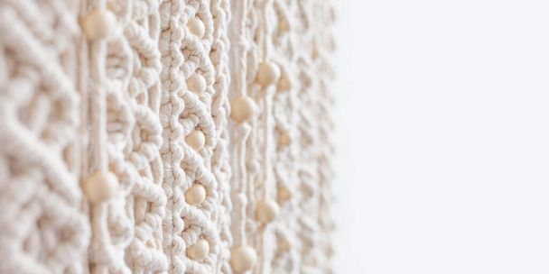Close-up of hand made macrame texture pattern with wooden beads. Eco friendly modern knitting. Natural decoration concept in the interior. Soft focus. Copy space. Banner - Zdjęcie, obraz