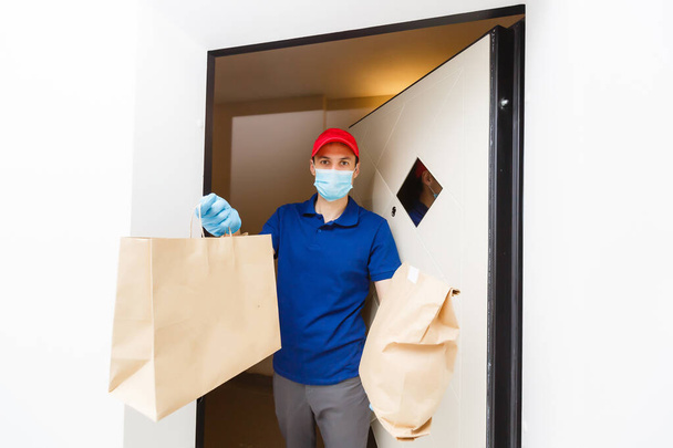 Доставщик держит картонные коробки в резиновых перчатках и маске. Интернет-магазины  - Фото, изображение
