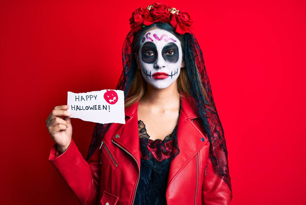 Donna che indossa il giorno del costume morto in possesso di felice atteggiamento di pensiero di carta di Halloween e espressione sobria guardando fiducioso di sé  - Foto, immagini
