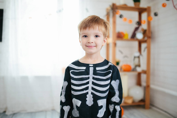 Holiday halloween. Funny little boy in a skeleton costume is ready to celebrate Halloween. Boy in a halloween dress-up room - Foto, Bild