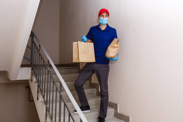 Uomo di consegna che tiene scatole di cartone in guanti di gomma e maschera. Shopping online  - Foto, immagini
