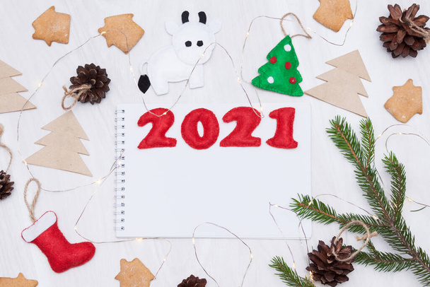 2021 christmas flat lay composition background. Bull symbol, cookies, felt toys, fir cones, lights. Note book for goals, wishes. - Photo, Image