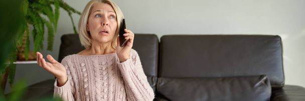 mulher em um telefonema sentado em um sofá na sala de estar em uma casa - Foto, Imagem