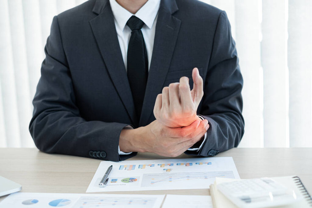 Businessman grasping the painful wrist caused by prolonged work on a laptop keyboard. Wrist numbness Arthritis While working at the office. - Photo, Image