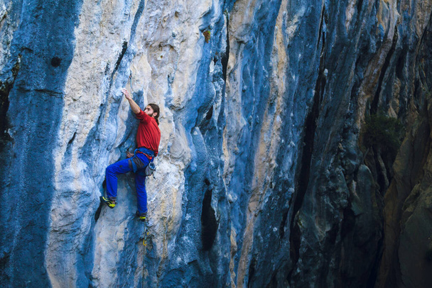 Silny człowiek wspina się na skałę, Wspinaczka skalna w Turcji, Trening wytrzymałościowy i siłowy, człowiek w sporcie ekstremalnym, Wspinaczka skalna trenuje w przyrodzie. - Zdjęcie, obraz