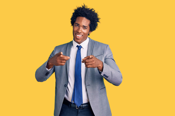 Hombre afroamericano guapo con el pelo afro usando chaqueta de negocios señalando los dedos a la cámara con la cara feliz y divertida. buena energía y vibraciones.  - Foto, Imagen