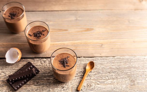 Mousse de chocolat maison en chocolat noir, œufs, crème fraîche et sucre sur une table en bois. - Photo, image