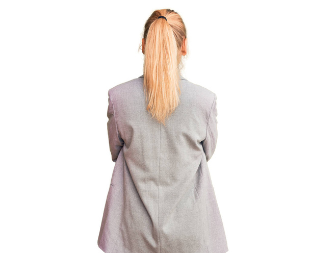 jonge mooie blonde vrouw dragen elegante jas staan achteruit weg te kijken met gekruiste armen  - Foto, afbeelding