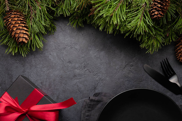 Tarjeta de felicitación navideña con abeto, plato y caja de regalo sobre fondo de piedra y espacio de copia para sus saludos de Navidad. Vista superior plano laico - Foto, imagen